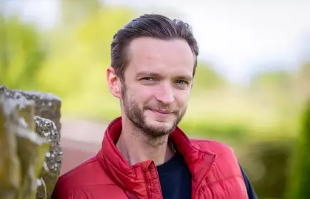Smiling man with a beard in a red vest